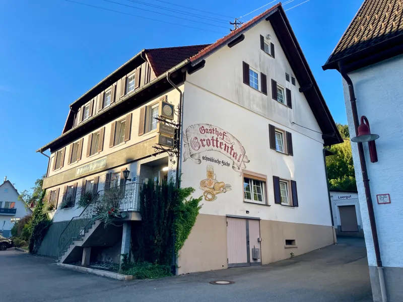 Dasselbe Haus heute, mit hellem Putz, Fensterläden und dem gemalten Schriftzug Gasthof Grottental