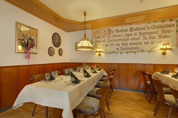 Die Gaststube mit gedeckten Tischen, an der Wand die gemalte Inschrift zur Hausgeschichte