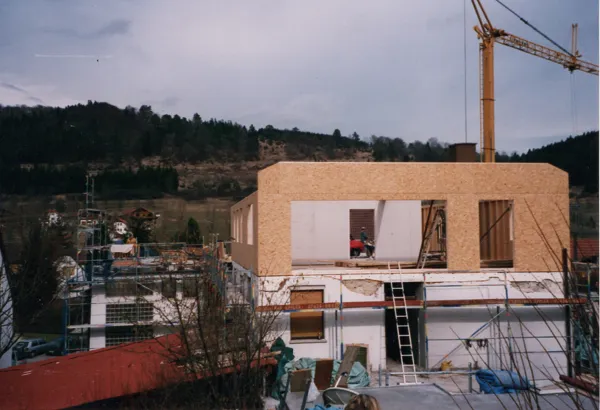 Ein Geschoss aus Holzelementen wird aufgesetzt, dahinter ein Baukran