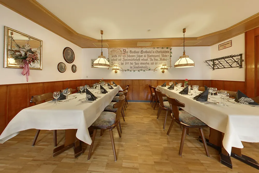 Die Gaststube mit Holzvertäfelung, gedeckten Tafeln und Hängelampen