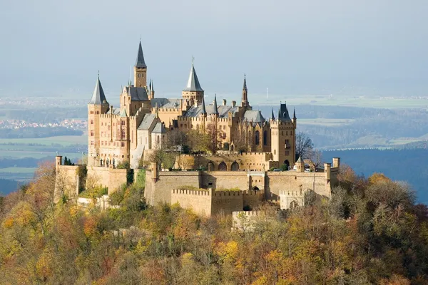 Burg Hohenzollern mit Türmen und Zinnen auf einem bewaldeten Bergkegel im Herbst