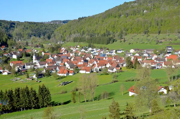 Blick über Oberdigisheim im Tal, dahinter bewaldete Hänge