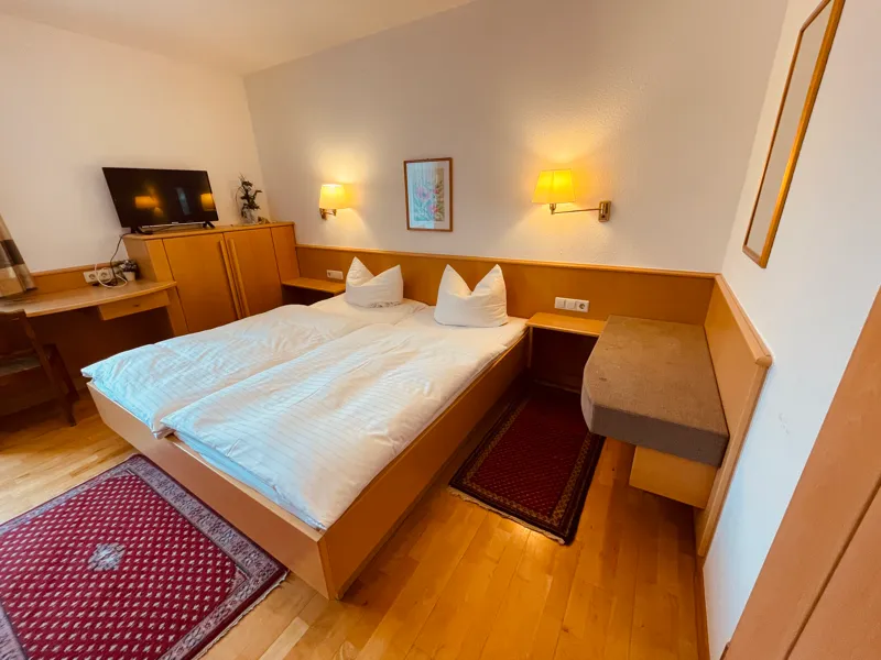 Doppelzimmer mit Doppelbett, Nachttischlampen und Fernseher