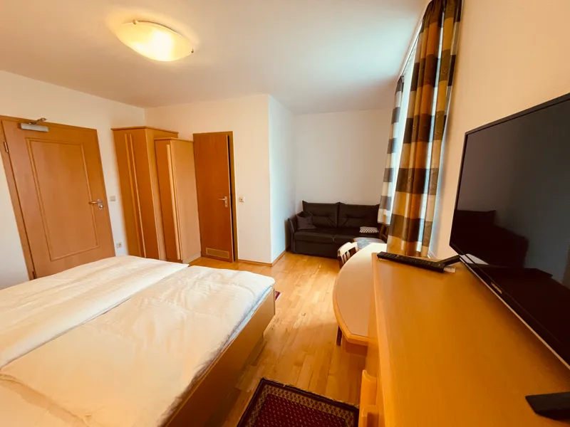 Suite mit Doppelbett, Fernseher und Sofa im Wohnbereich