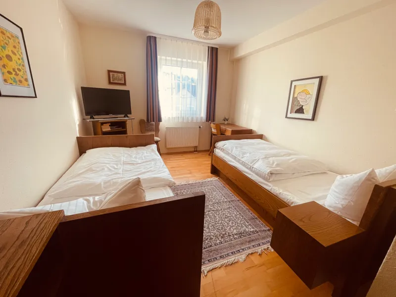 Zweibettzimmer mit zwei Einzelbetten, Fernseher und Fenster