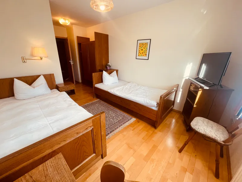 Zweibettzimmer mit Holzbetten und Sessel